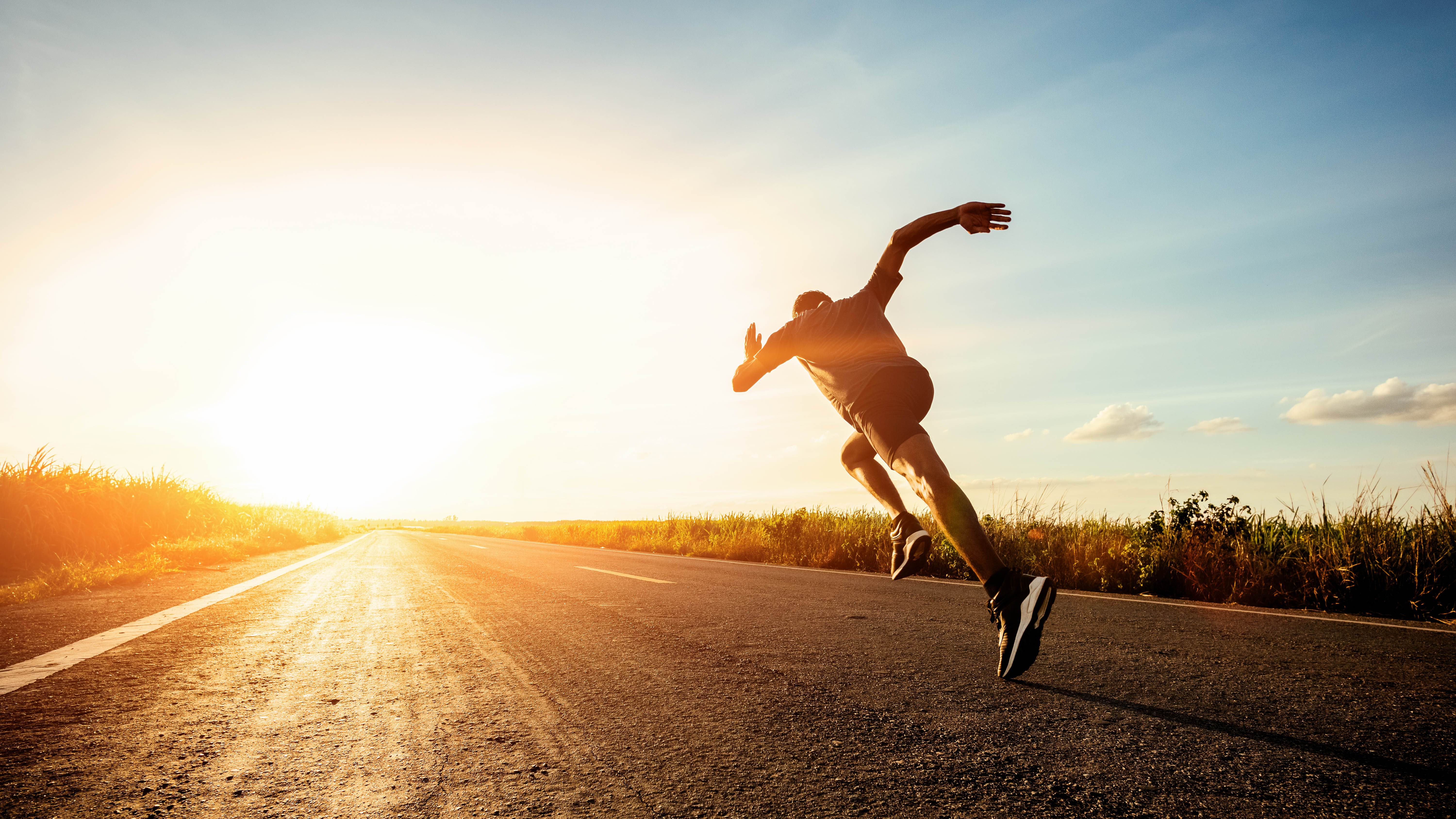 Fit man running along a back-country road, seemingly running right into the sunset. Fit man running along a back-country road, seemingly running right into the sunset.
